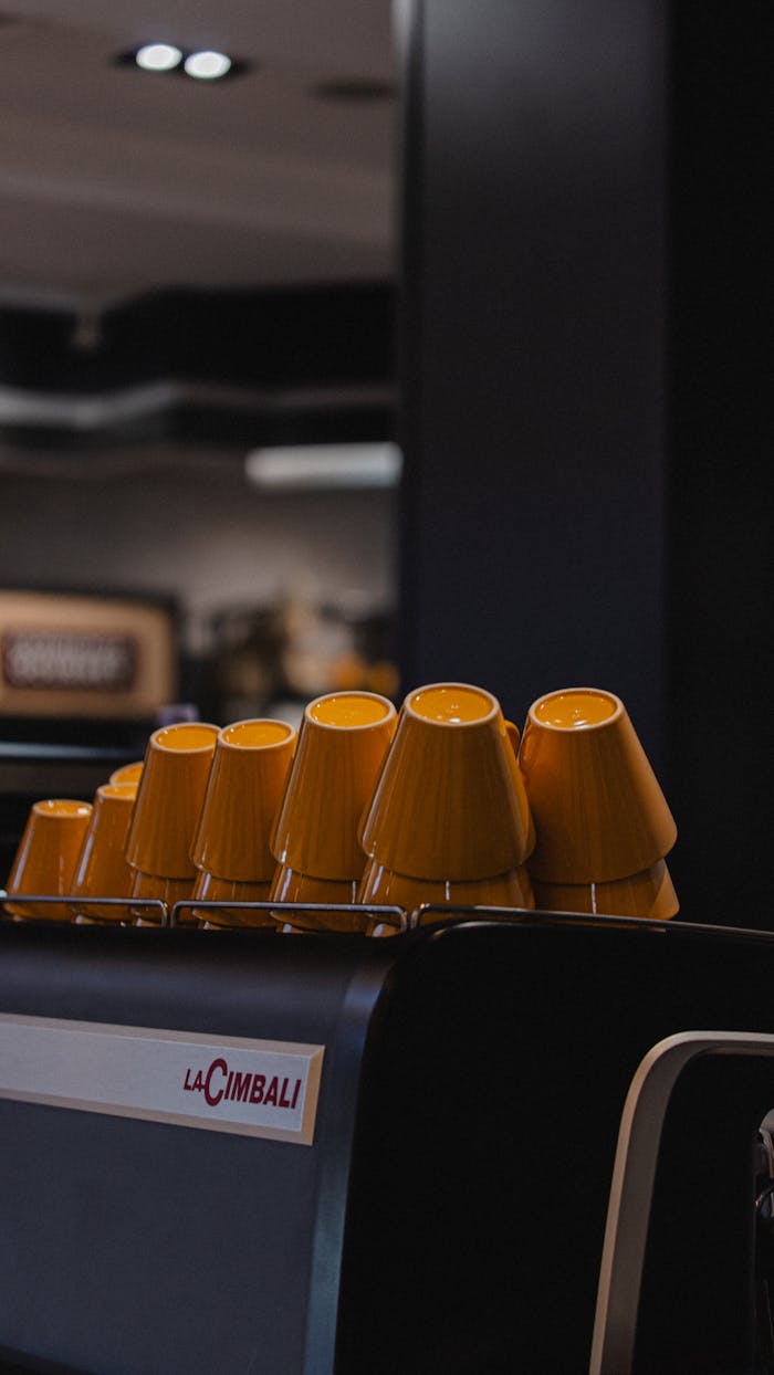Stylish yellow cups arranged on an espresso machine in a modern café interior.
